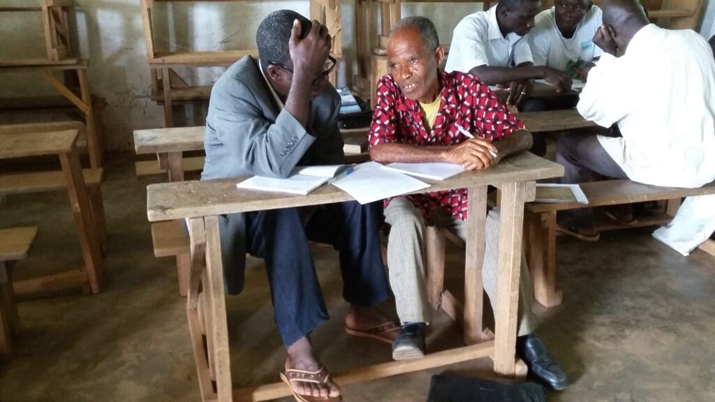 2 groups of West African men are working together on reading and writing in their own language.