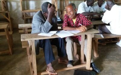 2 groups of West African men are working together on reading and writing in their own language.