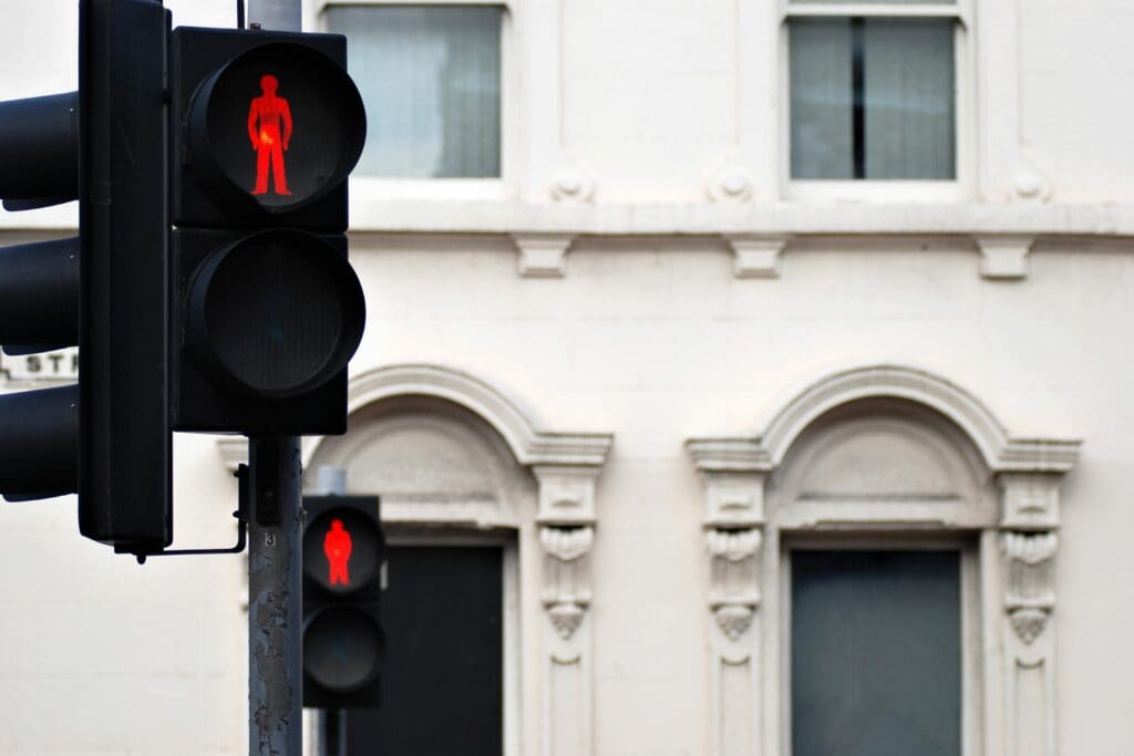 2 "Don't walk" stop lights are lit up red with European style mult-story building in the background.
