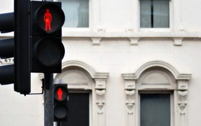 2 "Don't walk" stop lights are lit up red with European style mult-story building in the background.