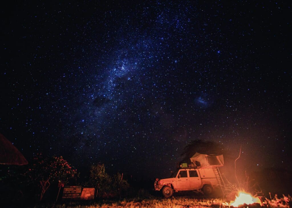 An East African evening under the stars. Supply filled SUV parked by the campfire.