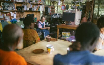 A Pioneer Bible, Marth Wade, is sitting and discussing Bible translation with Papua New Guineans