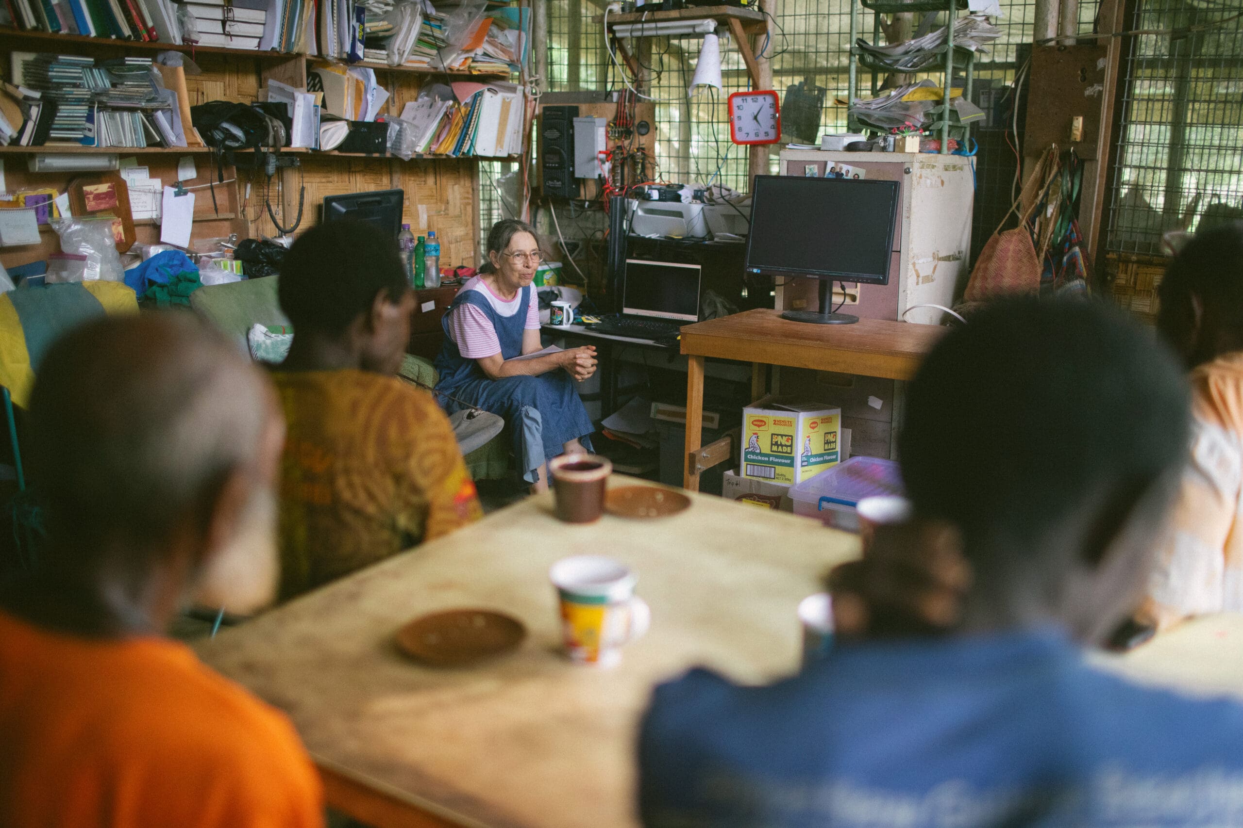 A Pioneer Bible, Marth Wade, is sitting and discussing Bible translation with Papua New Guineans